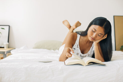 Junge Frau liegt im Bett und liest ein Buch - EBSF001558