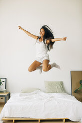 Exuberant young woman jumping on bed - EBSF001578