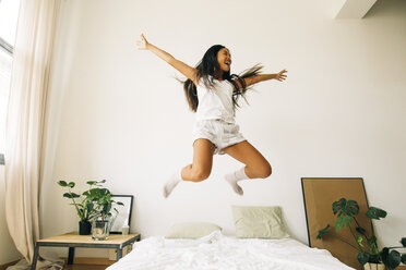 Übermütige junge Frau springt auf dem Bett - EBSF001579
