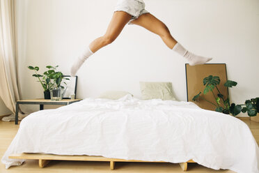 Legs of young woman jumping on bed - EBSF001580