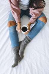 Frau mit Tasse Kaffee entspannt auf dem Bett, Teilansicht - EBSF001624