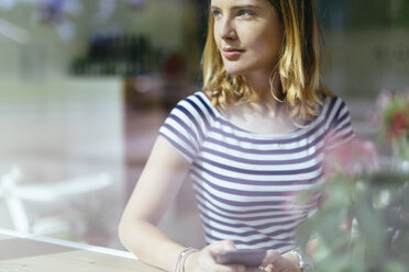 Young woman in a coffee shop looking through window - GIOF001315