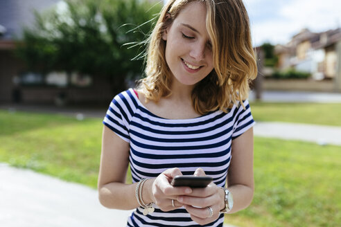 Lächelnde junge Frau mit Textnachrichten - GIOF001324