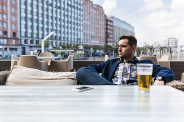 Junger Mann wartet in einem Straßencafé - MGOF002114