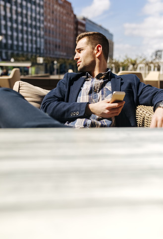 Junger Mann wartet in einem Straßencafé und beobachtet etwas, lizenzfreies Stockfoto