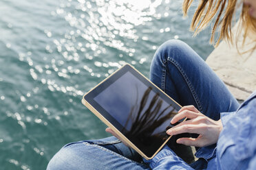 Young woman sitting on dock using digital tablet - BOYF000487