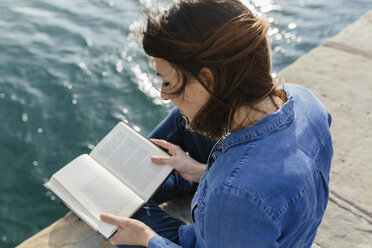 Junge Frau sitzt auf einem Steg und liest ein Buch - BOYF000489