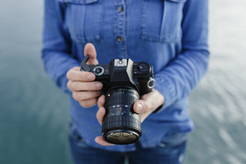 Junge Frau am Wasser mit Kamera in der Hand - BOYF000498