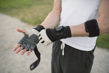 Young man putting on a training glove on the hand to train - RAEF001320