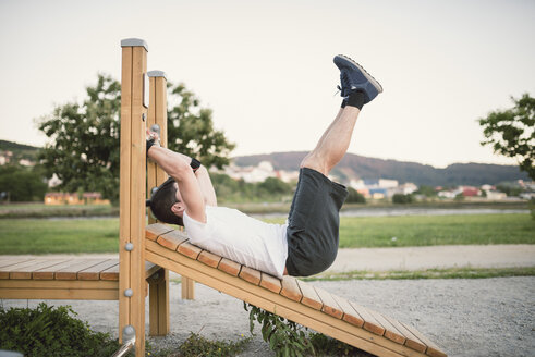 Junger Mann macht Sit-ups in einem Park, im Freien - RAEF001328