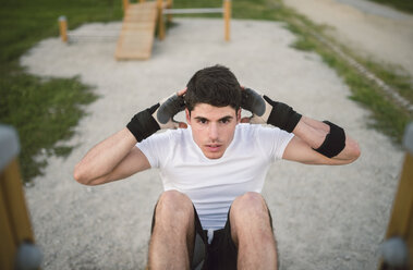 Young man doing sit-ups in a park, outdoors - RAEF001330