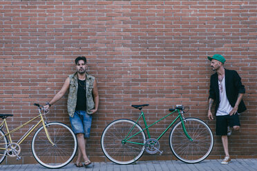 Two men with vintage bicycles leaning against brick wall - SKCF000125