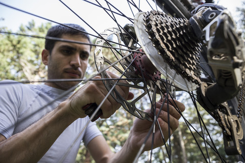 Mann, der das Rad eines Mountainbikes untersucht und einstellt, lizenzfreies Stockfoto
