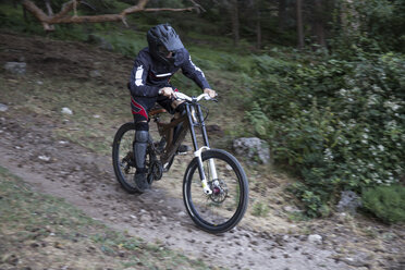 Mountainbiker fährt bergab auf einem Waldweg - ABZF000895