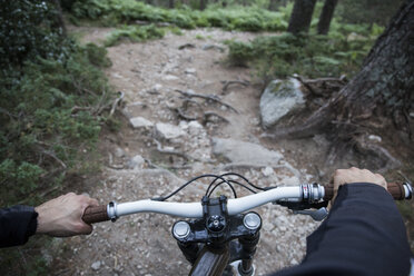Mountainbiker fährt bergab auf felsigem Pfad im Wald - ABZF000900
