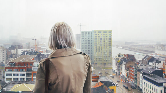 Belgien, Antwerpen, Rückenansicht einer Frau, die durch ein Fenster nach Eilandje schaut - RTBF000245