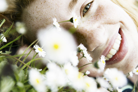 Lächelndes Mädchen auf einem Blumenfeld liegend, Nahaufnahme, lizenzfreies Stockfoto