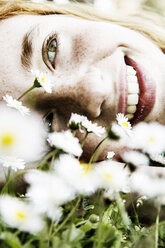 Lächelndes Mädchen auf einem Blumenfeld liegend, Nahaufnahme - JATF000883