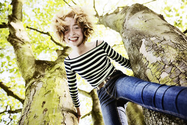 Lächelndes Mädchen klettert auf einen Baum - JATF000890