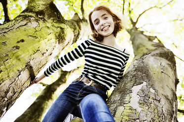 Smiling girl climbing on a tree - JATF000891