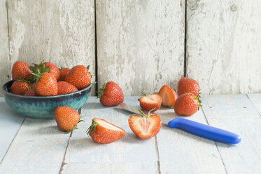 Bowl of strawberries and kitchen knife on wood - ASF005955