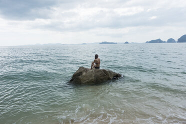 Thailand, Tubkaek, back view of woman sitting on rock looking at sea - JATF000900