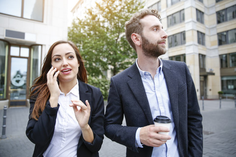 Geschäftsmann und Geschäftsfrau mit Handy und Kaffee zum Mitnehmen im Freien, lizenzfreies Stockfoto