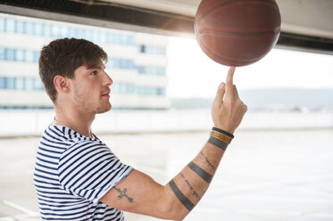 Young man balancing basketball on finger - DIGF000828
