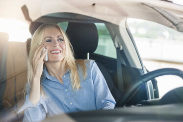 Smiling woman in car on cell phone - DIGF000831