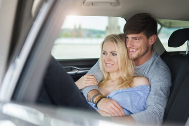 Lächelndes, verliebtes Paar auf dem Rücksitz eines Autos - DIGF000836