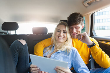 Happy couple with digital tablet on back seat of a car - DIGF000841