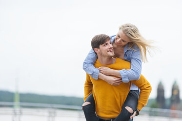 Happy young man carrying his girfriend piggyback - DIGF000844