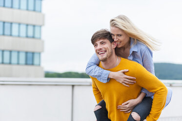 Happy young man carrying his girfriend piggyback - DIGF000846