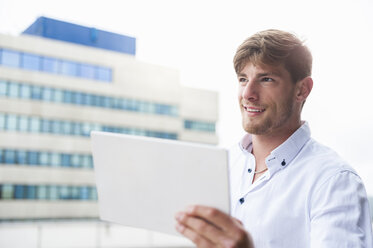 Junger Mann hält digitales Tablet im Freien - DIGF000852