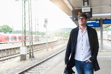 Lächelnder junger Mann auf dem Bahnsteig - DIGF000855