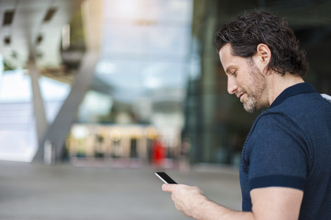 Smiling businessman looking at smartphone stock photo