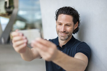 Porträt eines lächelnden Mannes, der ein Selfie mit einem Mobiltelefon macht - DIGF000909
