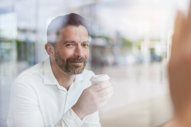 Portrait of smiling businessman in a coffee shop looking through window - DIGF000911