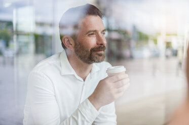 Portrait of relaxed businessman looking through window of coffee shop - DIGF000912