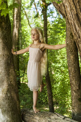 Blond little girl balancing on tree trunk - TCF005029