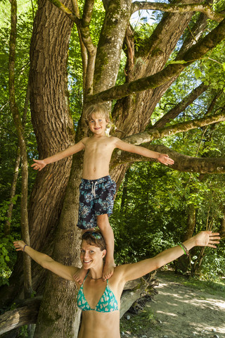 Kleiner Junge balanciert auf den Schultern seiner Mutter, lizenzfreies Stockfoto