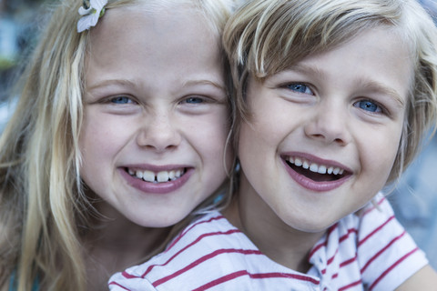 Porträt eines lächelnden kleinen Jungen und seiner Schwester Kopf an Kopf, lizenzfreies Stockfoto