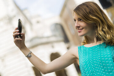 Lächelnde junge Frau macht Selfie mit Smartphone - GIOF001348