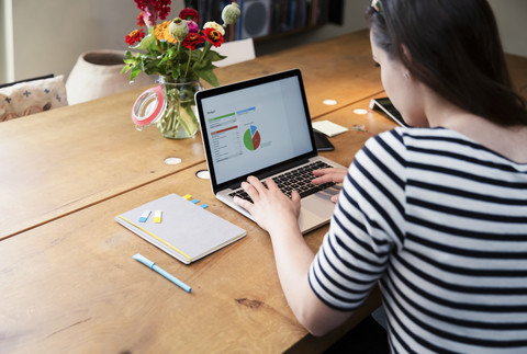 Frau am Schreibtisch mit Laptop, die an einer Berechnung arbeitet, lizenzfreies Stockfoto