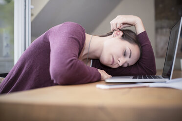 Müde junge Frau schläft am Schreibtisch - REAF000119