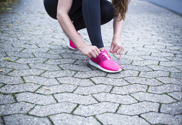 Sportliche junge Frau, die ihre Schuhe bindet - REAF000137