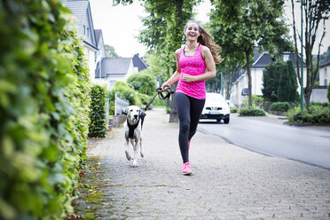 Junge Frau joggt mit Hund - REAF000140