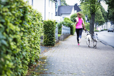Junge Frau beim Joggen mit zwei Hunden - REAF000142