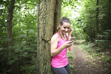 Sportive young woman with smartphone and earbuds - REAF000147