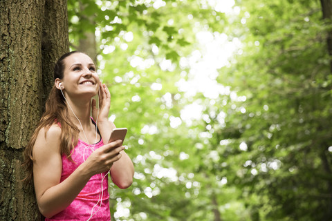Sportive young woman with smartphone and earbuds stock photo